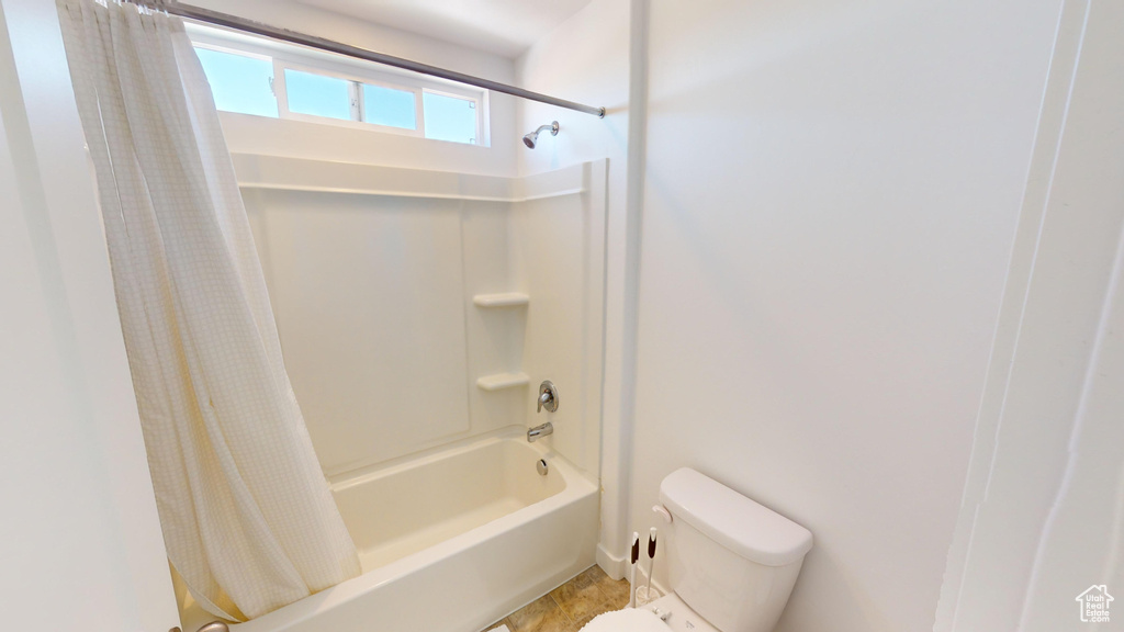 Bathroom with tile patterned floors, toilet, and shower / bath combination with curtain