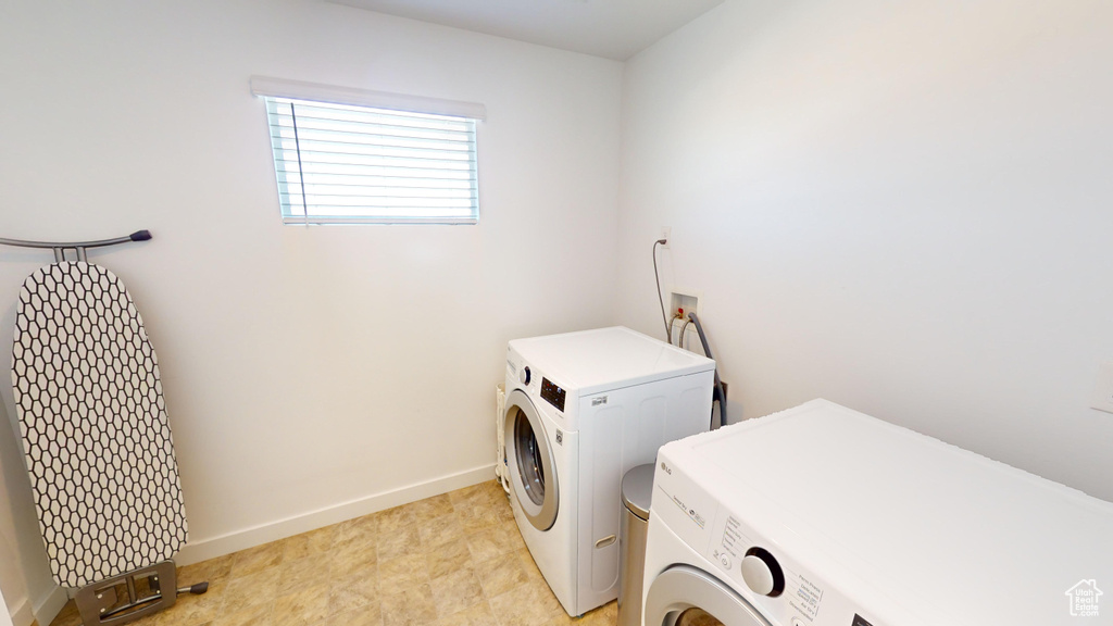 Washroom with separate washer and dryer and light tile patterned floors