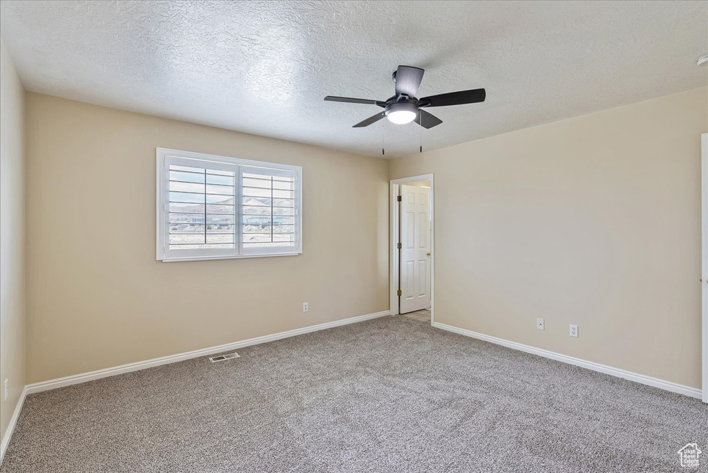 Carpeted spare room featuring a textured ceiling and ceiling fan