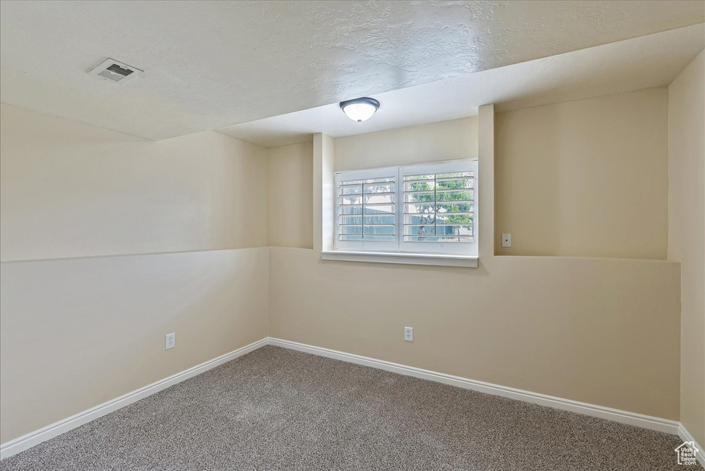 Empty room featuring carpet flooring and a textured ceiling