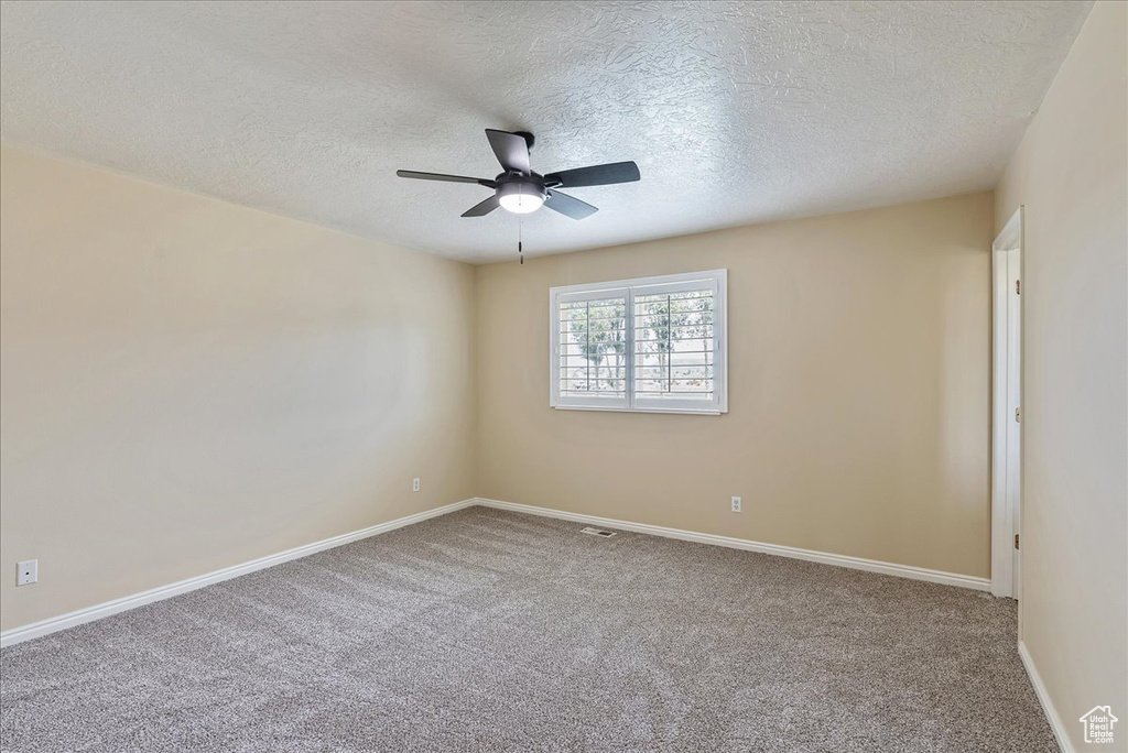 Unfurnished room featuring carpet floors, a textured ceiling, and ceiling fan