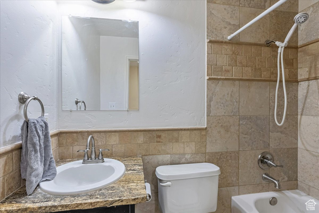 Full bathroom featuring vanity, tiled shower / bath, tasteful backsplash, and toilet