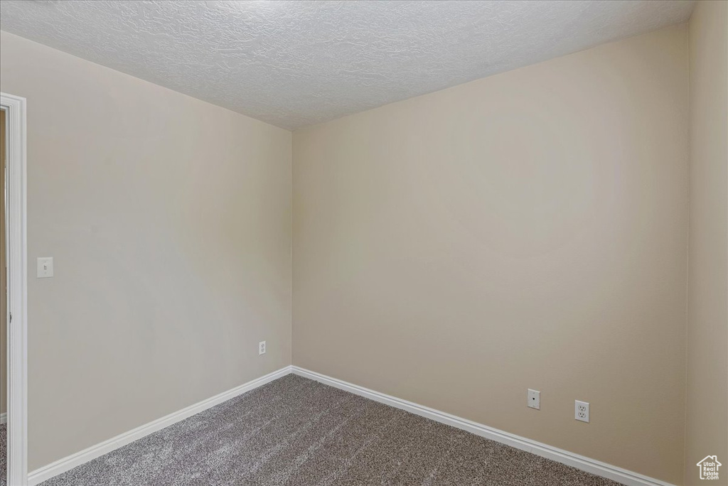 Carpeted spare room featuring a textured ceiling