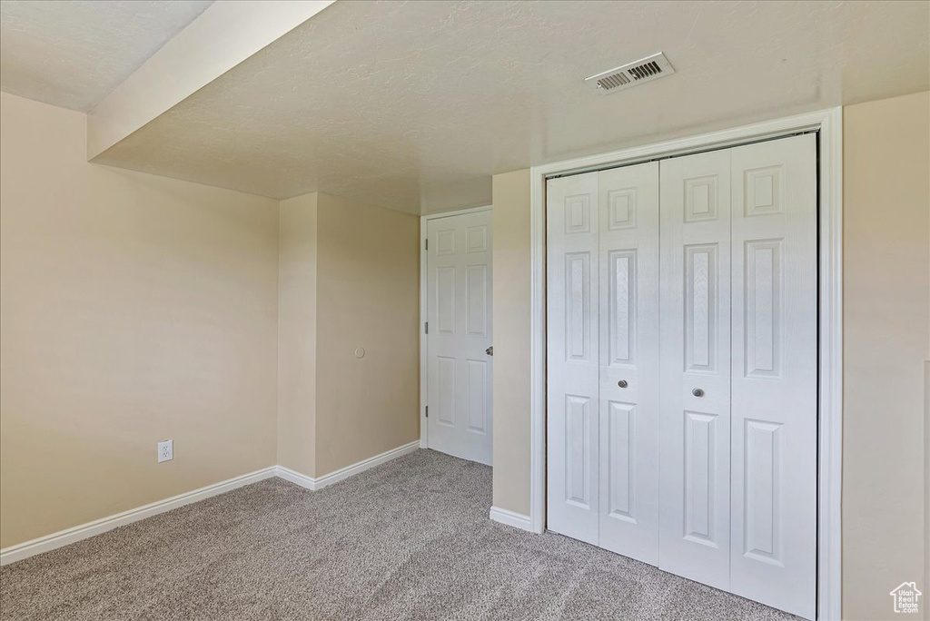 Unfurnished bedroom with a textured ceiling, a closet, and carpet flooring