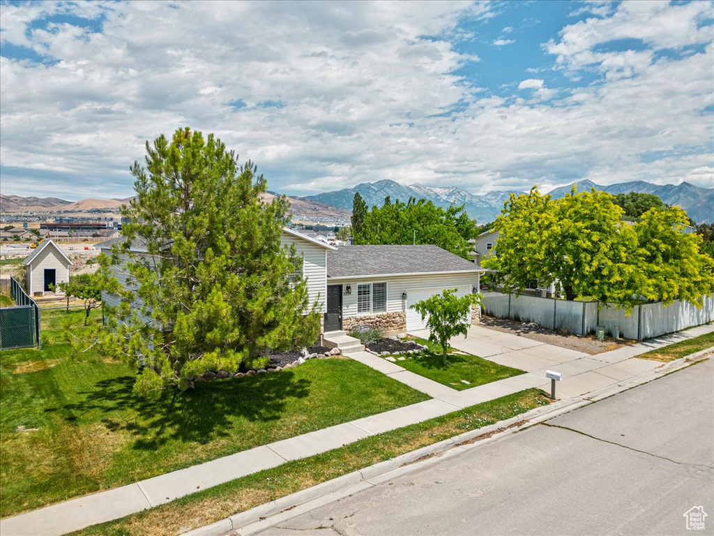 View of property hidden behind natural elements with a mountain view and a front yard