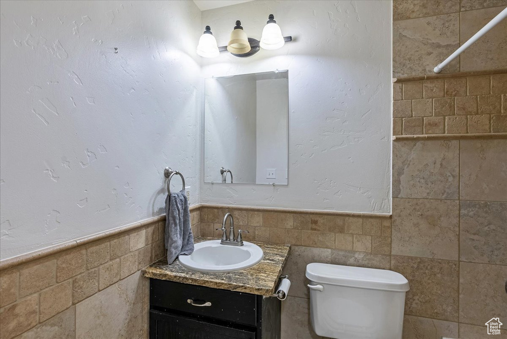 Bathroom featuring vanity, tasteful backsplash, toilet, and tile walls