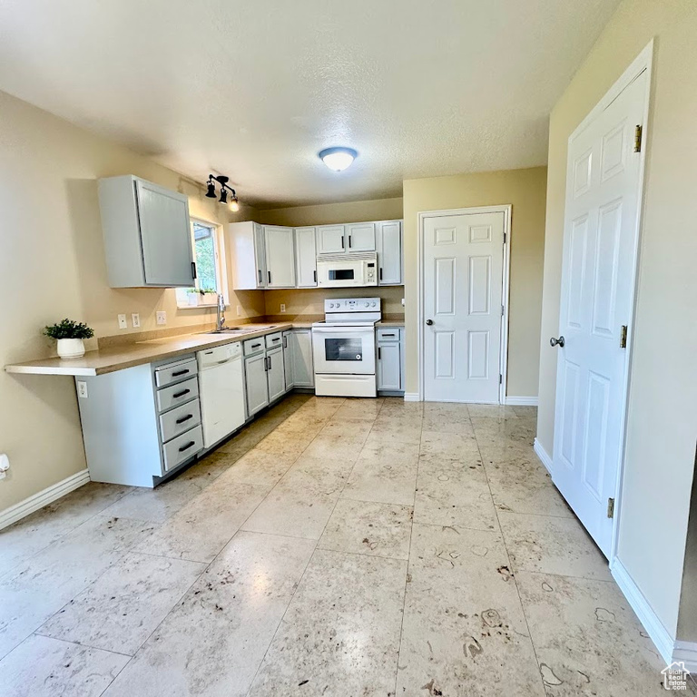 Kitchen with a textured ceiling, white appliances, and light tile patterned floors