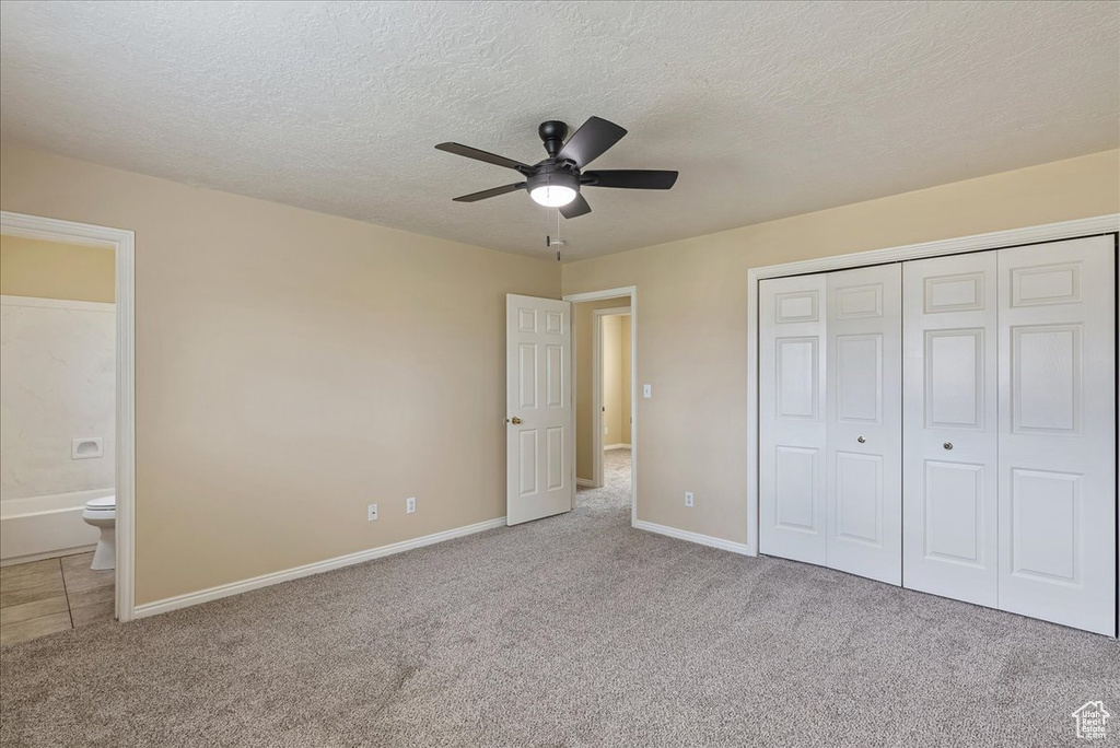 Unfurnished bedroom featuring ceiling fan, connected bathroom, carpet flooring, and a closet