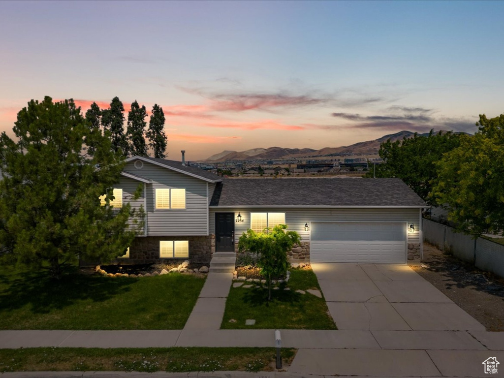 Split level home with a garage, a yard, and a mountain view