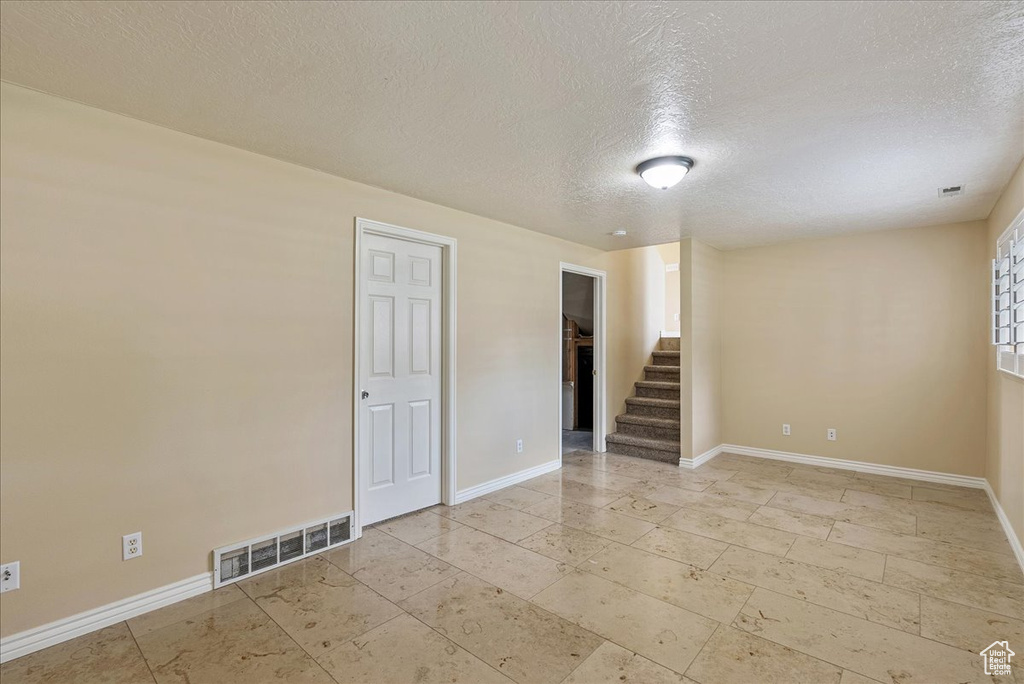 Tiled spare room featuring a textured ceiling