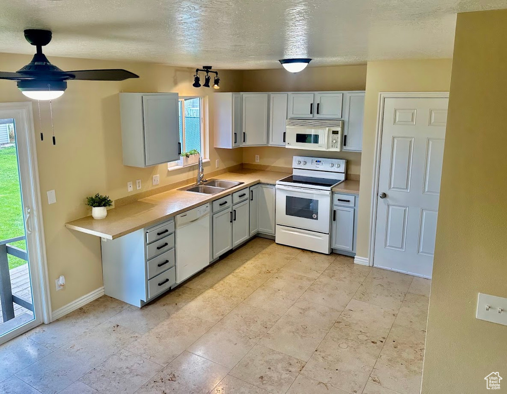 Kitchen with a wealth of natural light, white appliances, light tile patterned floors, and sink