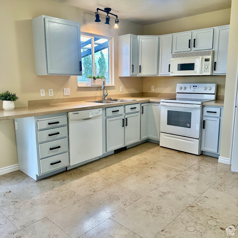 Kitchen featuring sink, white appliances, and light tile patterned flooring