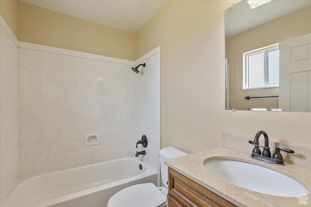 Full bathroom with a textured ceiling, toilet, vanity, and shower / tub combination