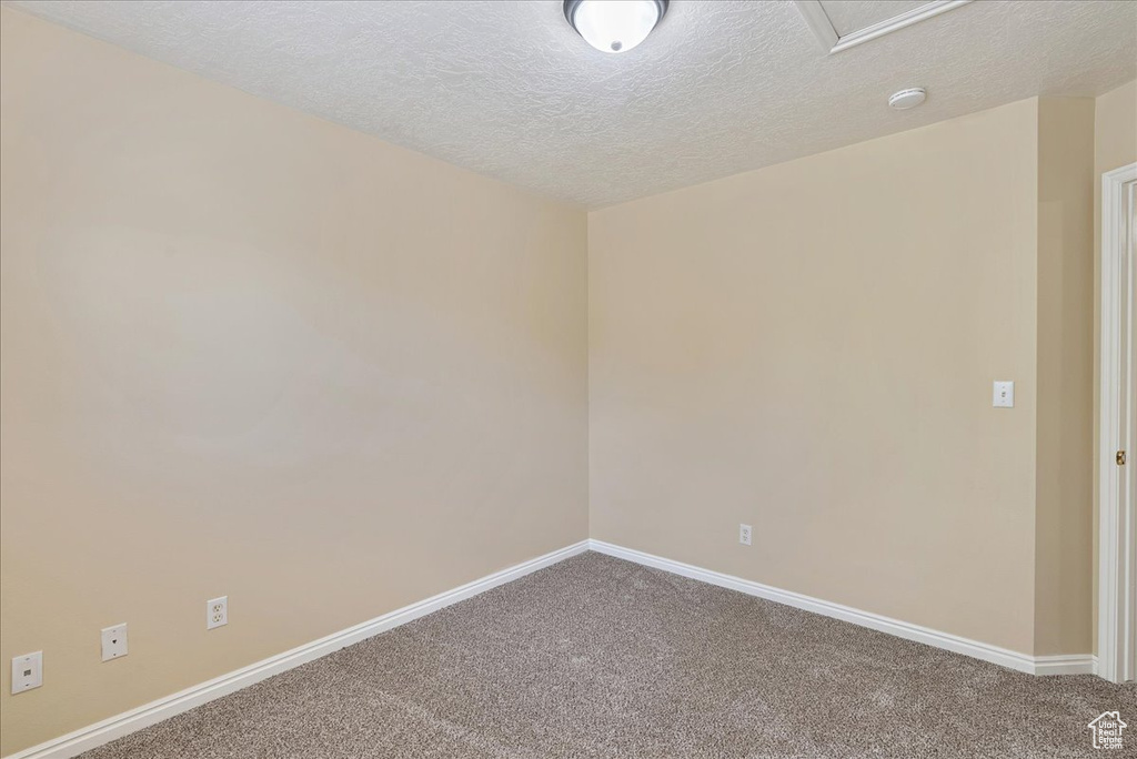 Carpeted spare room featuring a textured ceiling