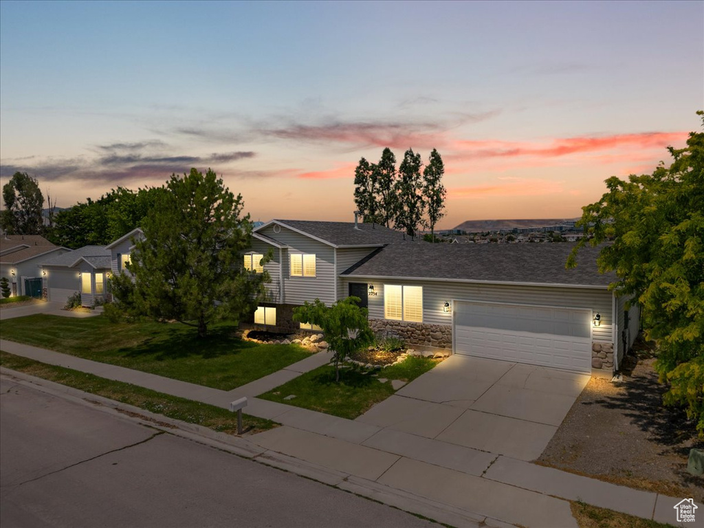 View of front of property featuring a garage and a yard