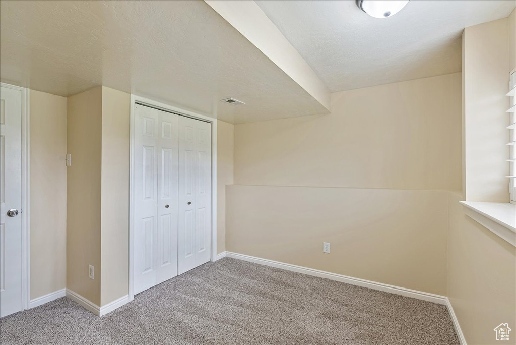 Unfurnished bedroom with a textured ceiling, a closet, and carpet