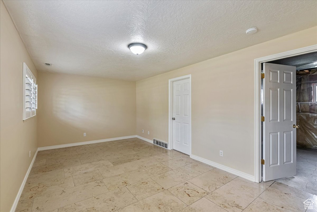 Empty room featuring light tile patterned floors and a textured ceiling