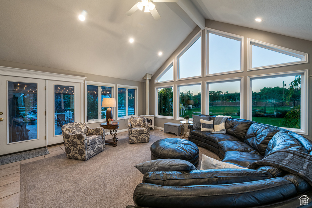 Tiled living room featuring beamed ceiling, ceiling fan, and high vaulted ceiling