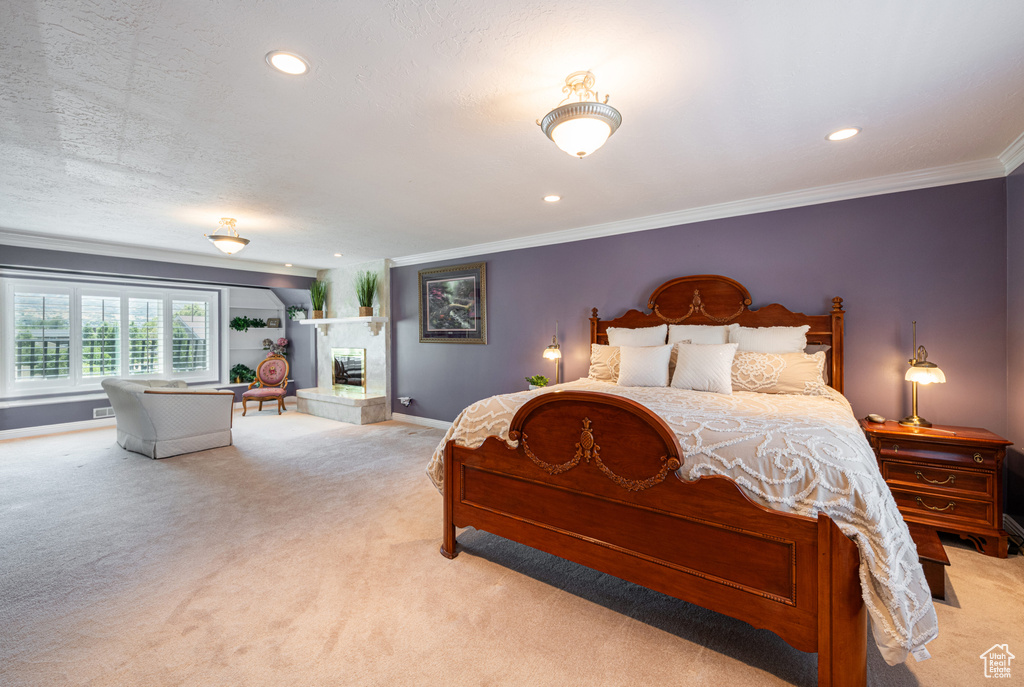 Carpeted bedroom featuring crown molding, a textured ceiling, and a tiled fireplace