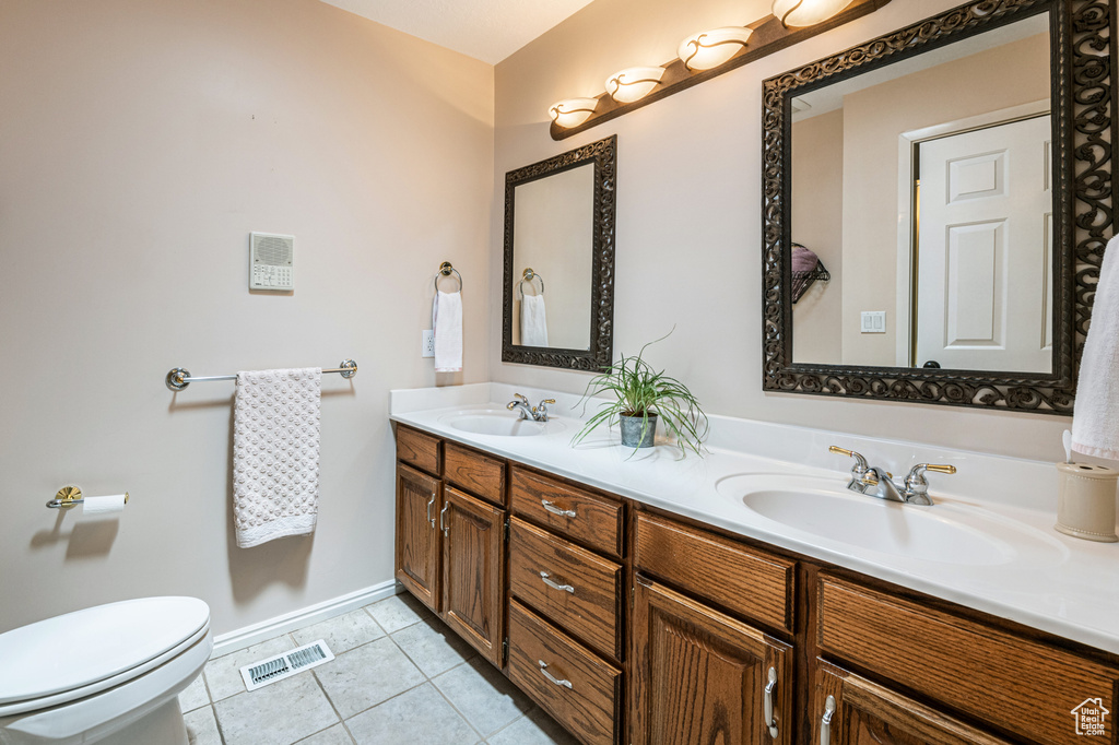 Bathroom featuring toilet, tile patterned floors, and double sink vanity