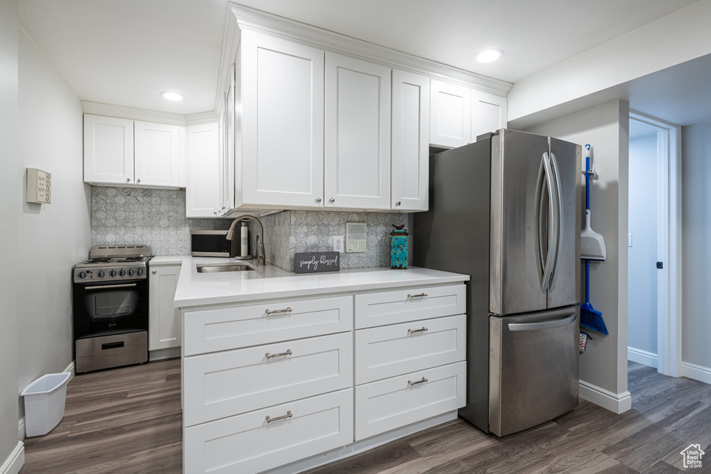 Kitchen with dark hardwood / wood-style floors, stainless steel appliances, sink, and white cabinets