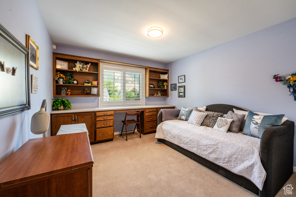 Carpeted bedroom featuring built in desk