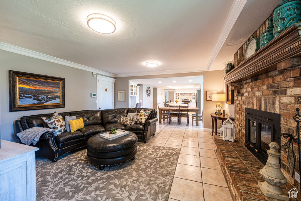 Living room with crown molding, a brick fireplace, and light tile patterned floors