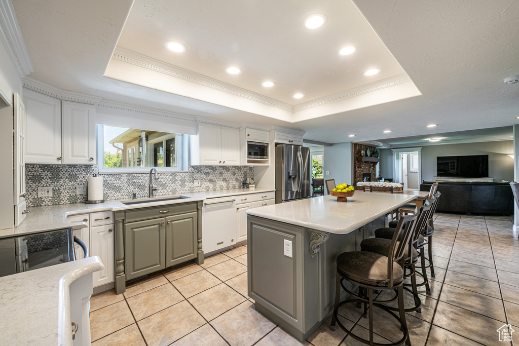 Kitchen featuring stainless steel appliances, a raised ceiling, sink, and backsplash