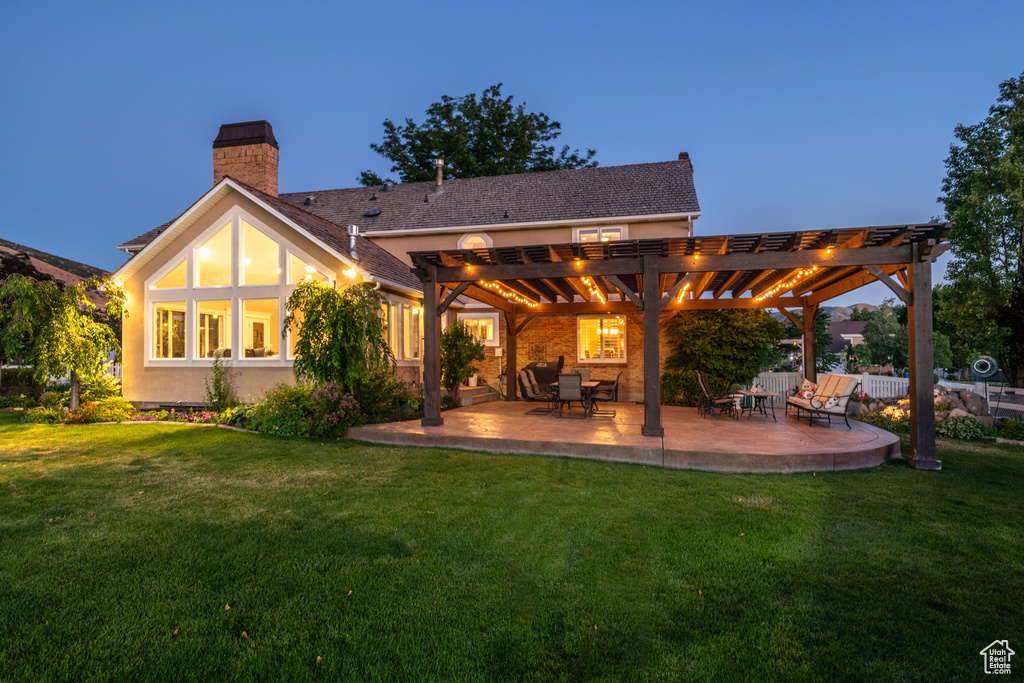 Back of property featuring a pergola, a patio, and a lawn