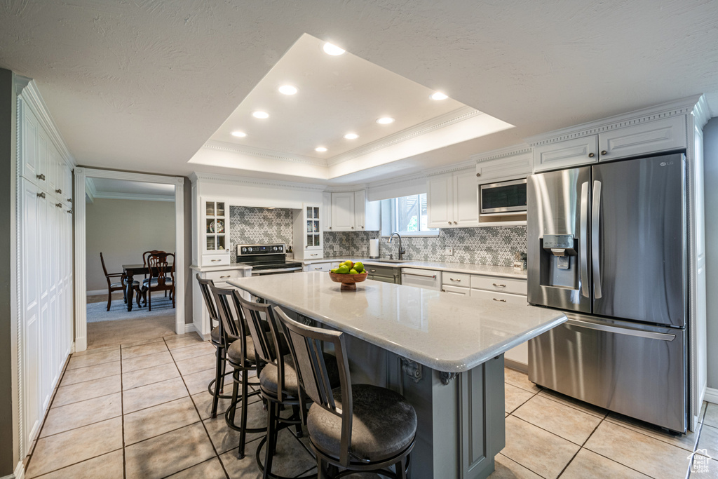 Kitchen featuring a center island, a tray ceiling, stainless steel appliances, and backsplash