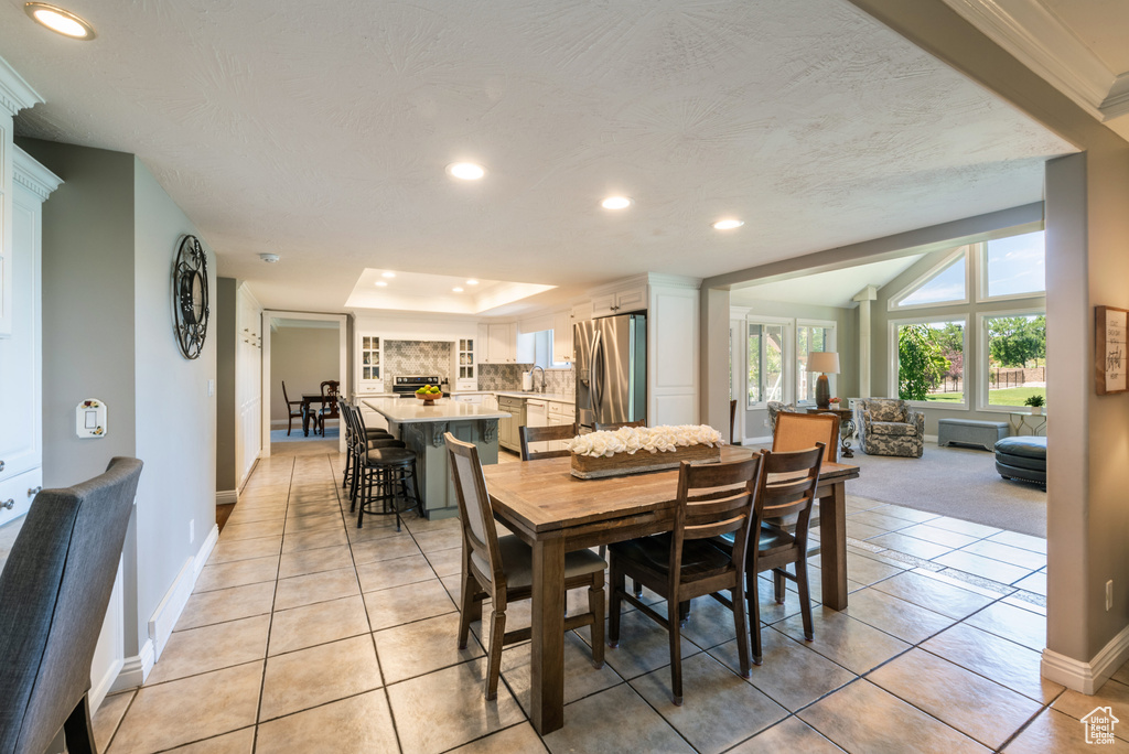 Tiled dining room with a raised ceiling