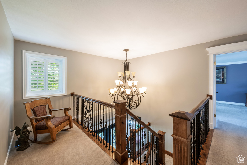 Hallway with a notable chandelier and carpet floors