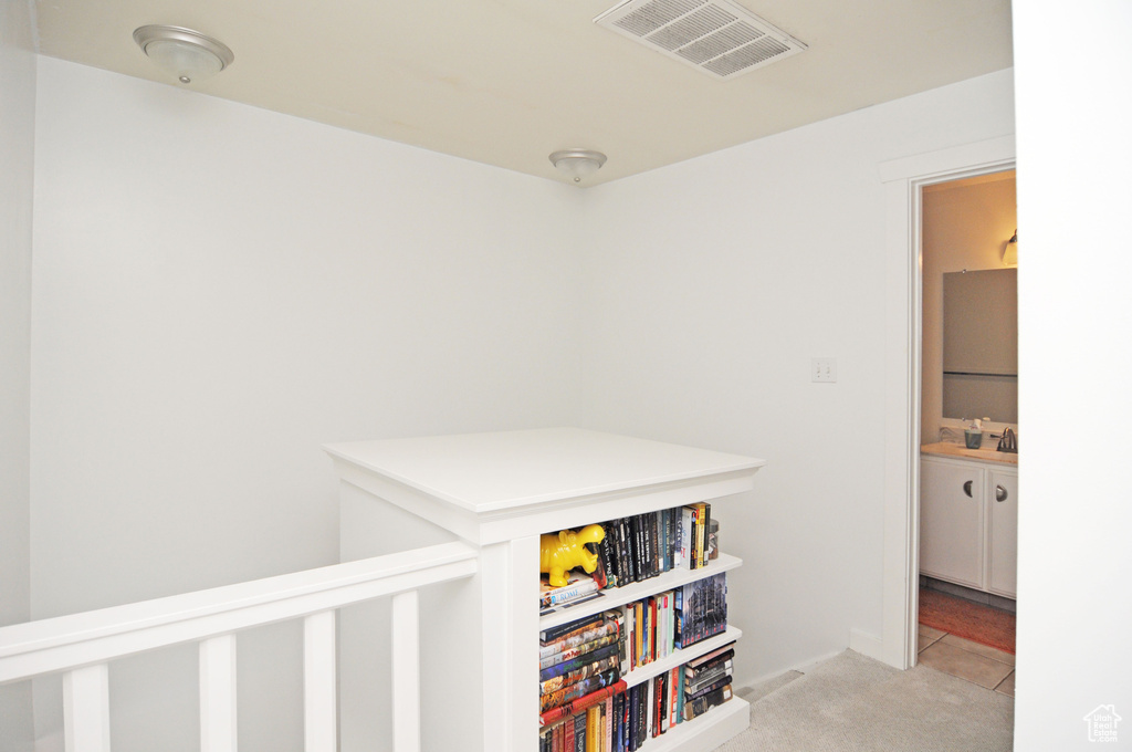 Corridor featuring light carpet and sink