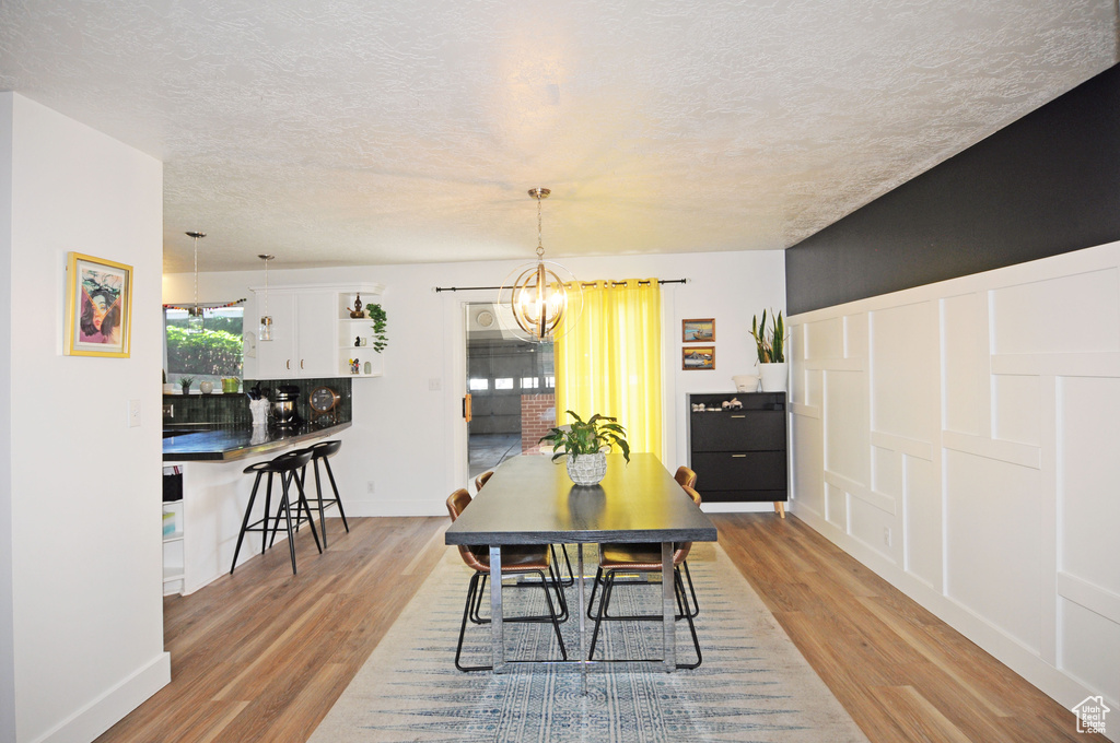 Dining space featuring a chandelier, light wood-type flooring, and a textured ceiling