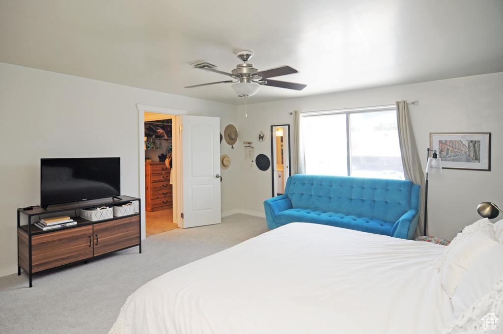 Bedroom with a closet, light carpet, a spacious closet, and ceiling fan