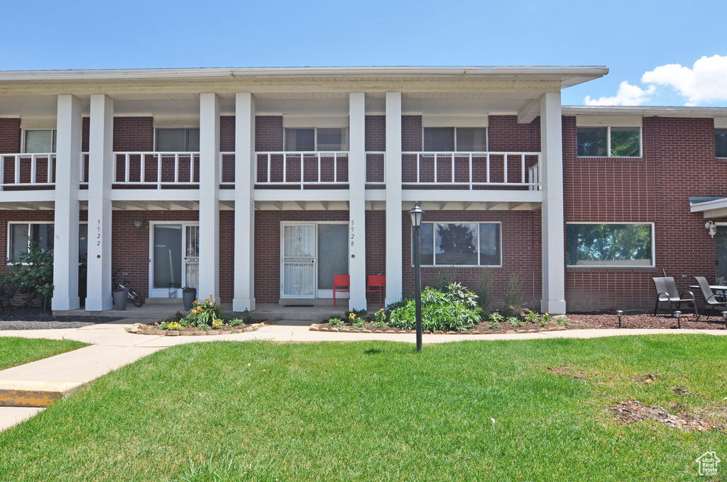 View of front facade with a balcony and a front lawn