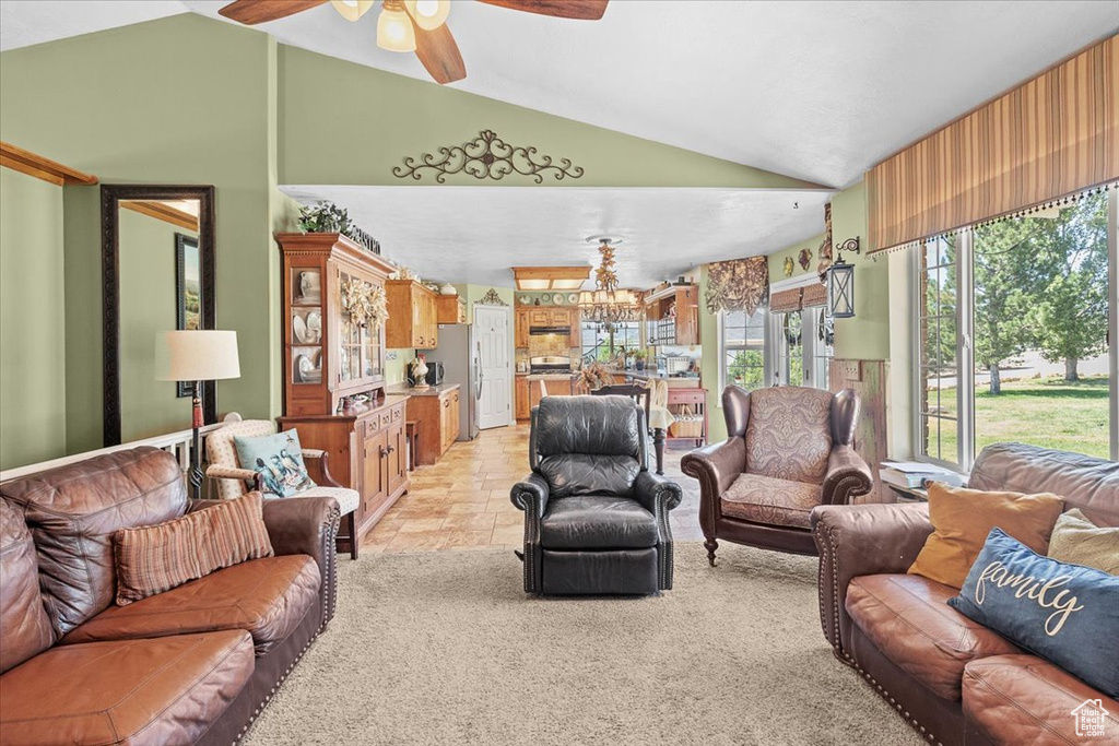 Living room featuring ceiling fan with notable chandelier, lofted ceiling, and light tile patterned floors