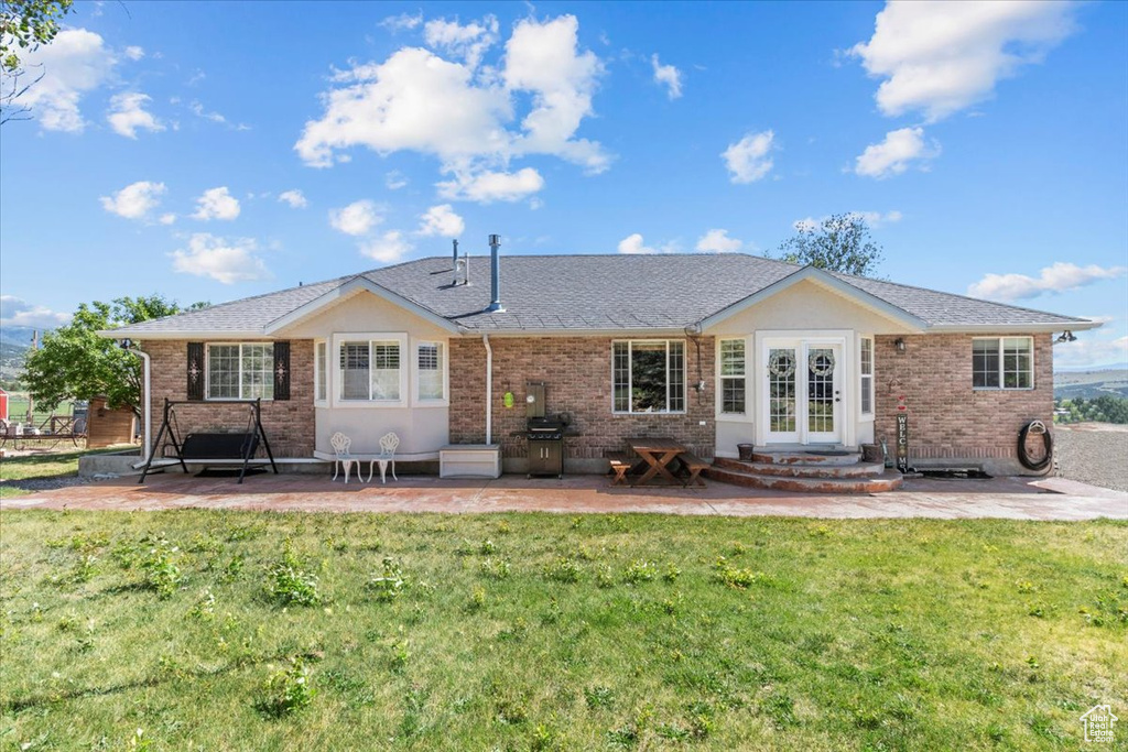 Rear view of house featuring a patio, a yard, and french doors