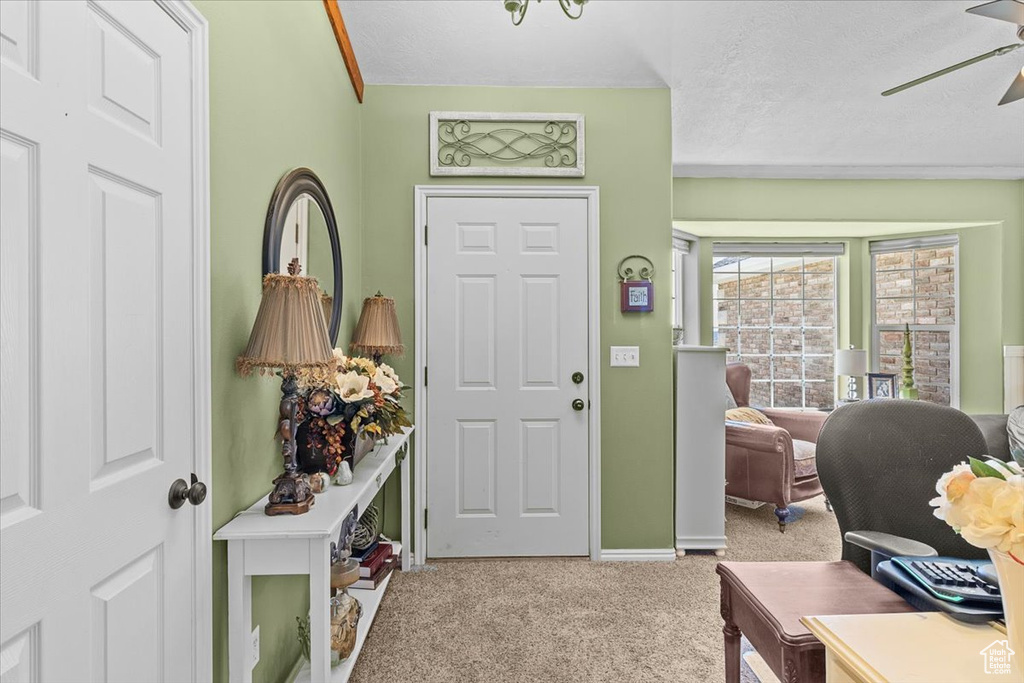 Entrance foyer featuring carpet, ceiling fan, and a textured ceiling