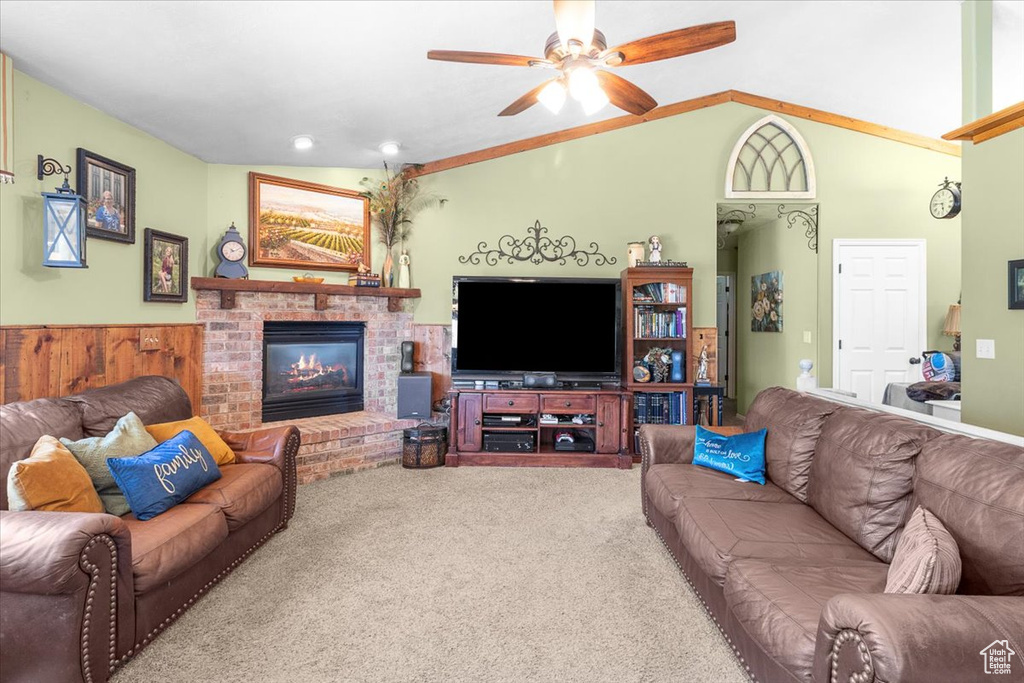 Living room with a fireplace, ceiling fan, lofted ceiling, and carpet flooring