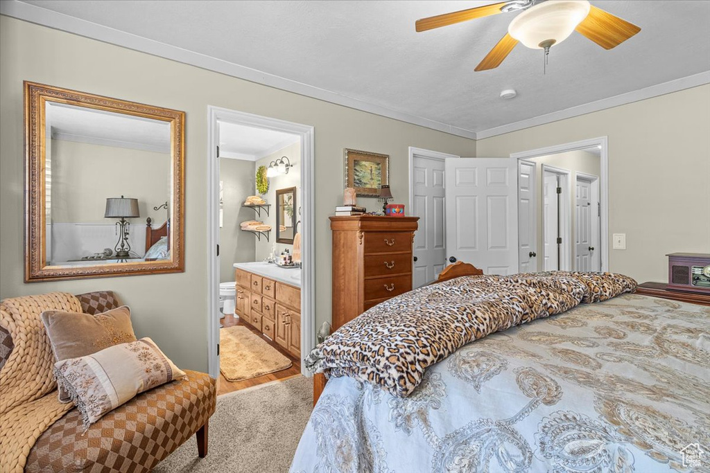 Carpeted bedroom featuring ceiling fan, connected bathroom, and ornamental molding