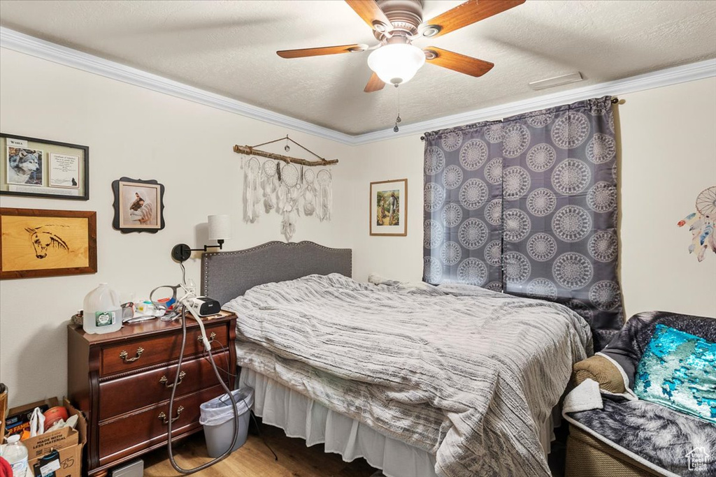 Bedroom featuring ceiling fan, crown molding, a textured ceiling, and hardwood / wood-style flooring