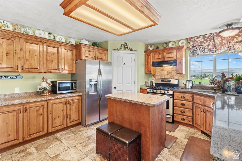 Kitchen featuring a kitchen island, sink, stainless steel appliances, and light tile patterned floors