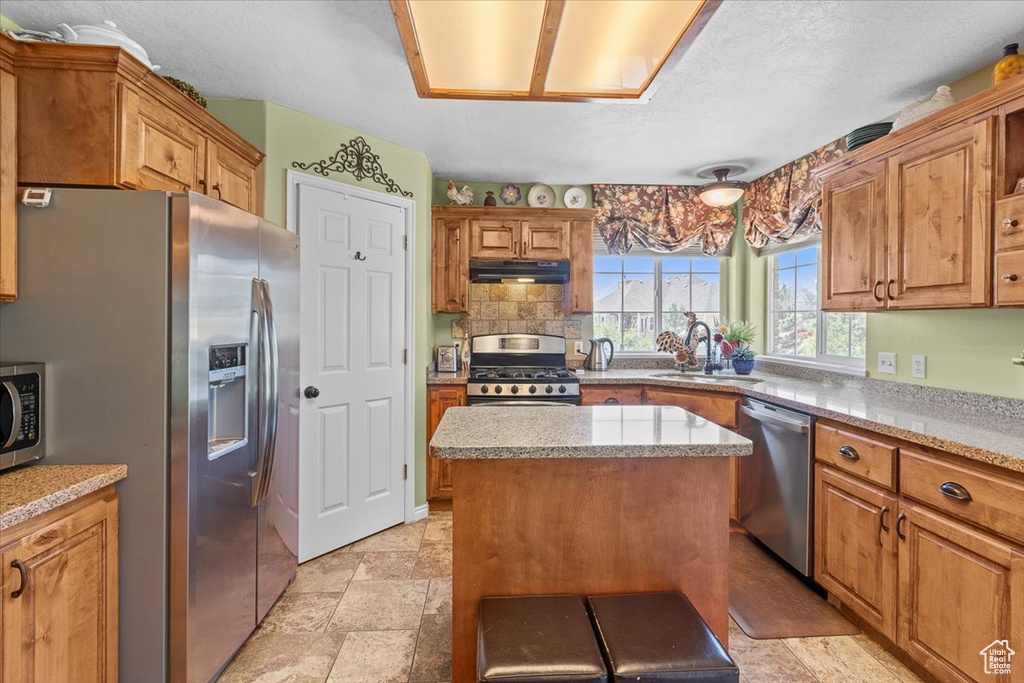 Kitchen with light tile patterned flooring, stainless steel appliances, sink, and a kitchen island