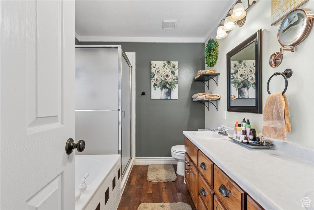 Full bathroom featuring vanity, shower with separate bathtub, hardwood / wood-style flooring, and toilet