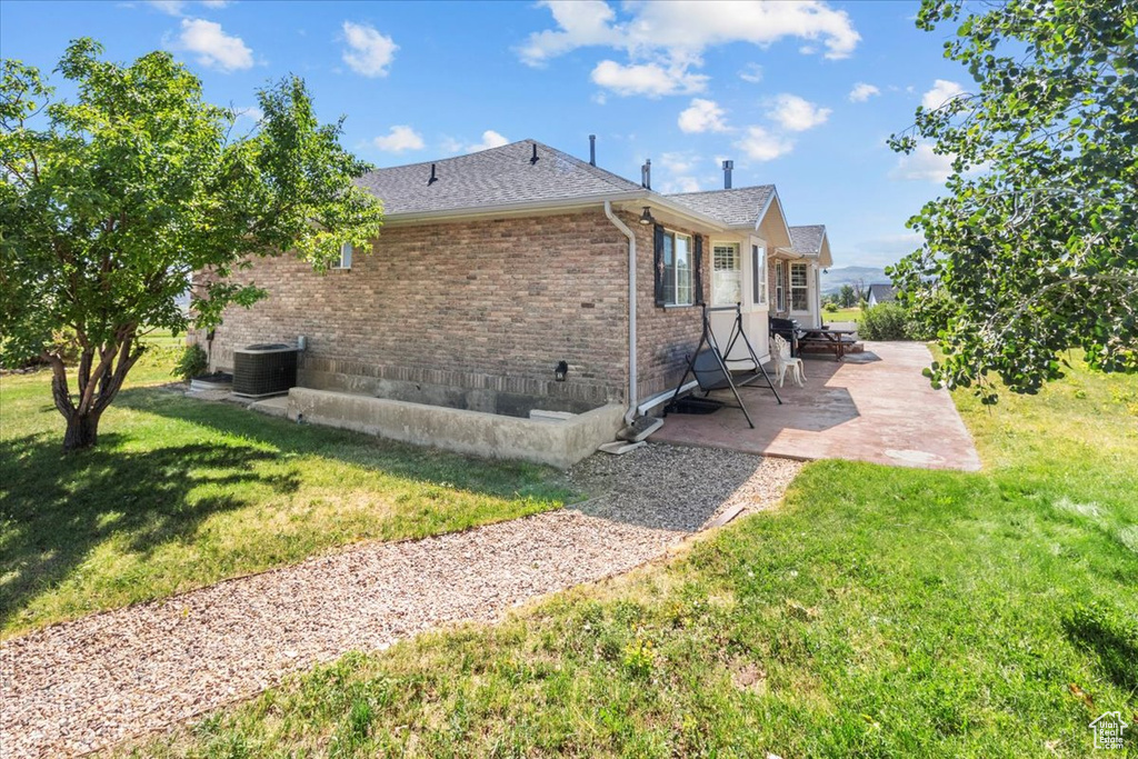 View of home's exterior with a patio area, a lawn, and central AC unit