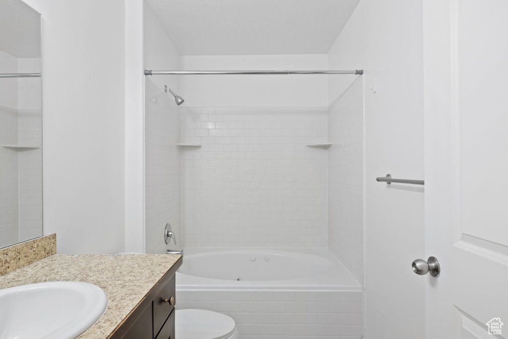 Full bathroom with toilet, vanity, and tiled shower / bath