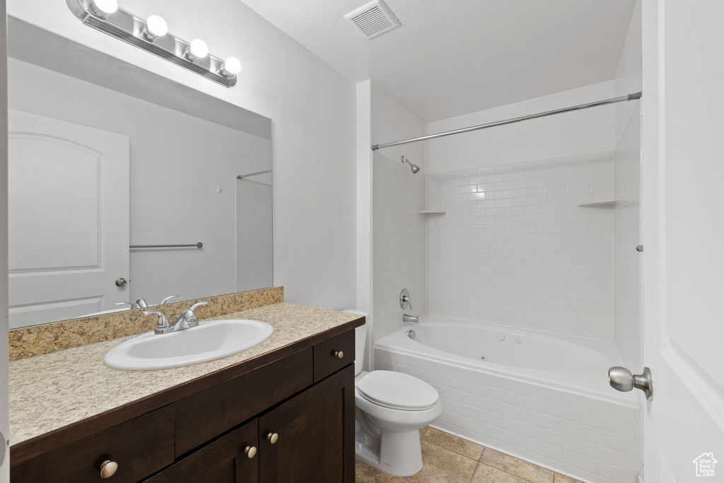 Full bathroom featuring vanity, tile patterned flooring, tiled shower / bath, and toilet