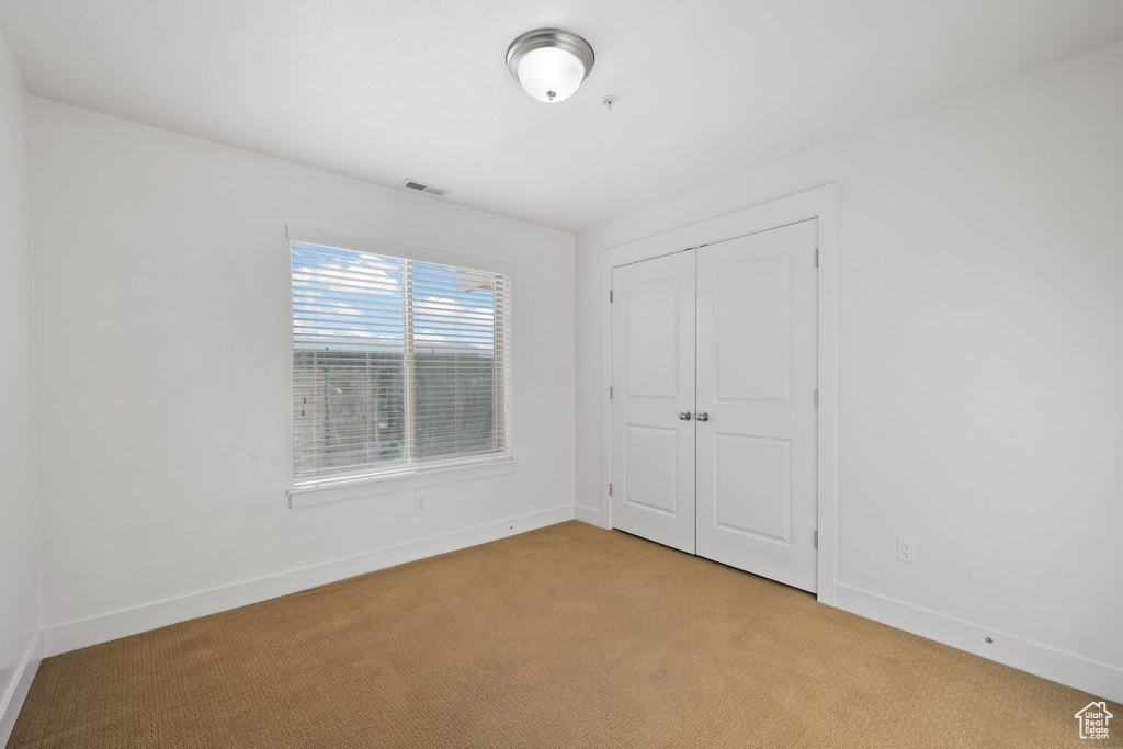 Unfurnished bedroom featuring light carpet and a closet