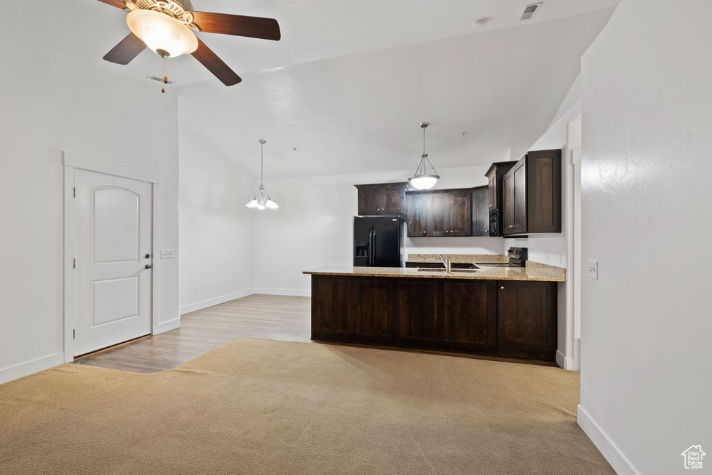 Kitchen with decorative light fixtures, black appliances, ceiling fan with notable chandelier, dark brown cabinetry, and light hardwood / wood-style flooring